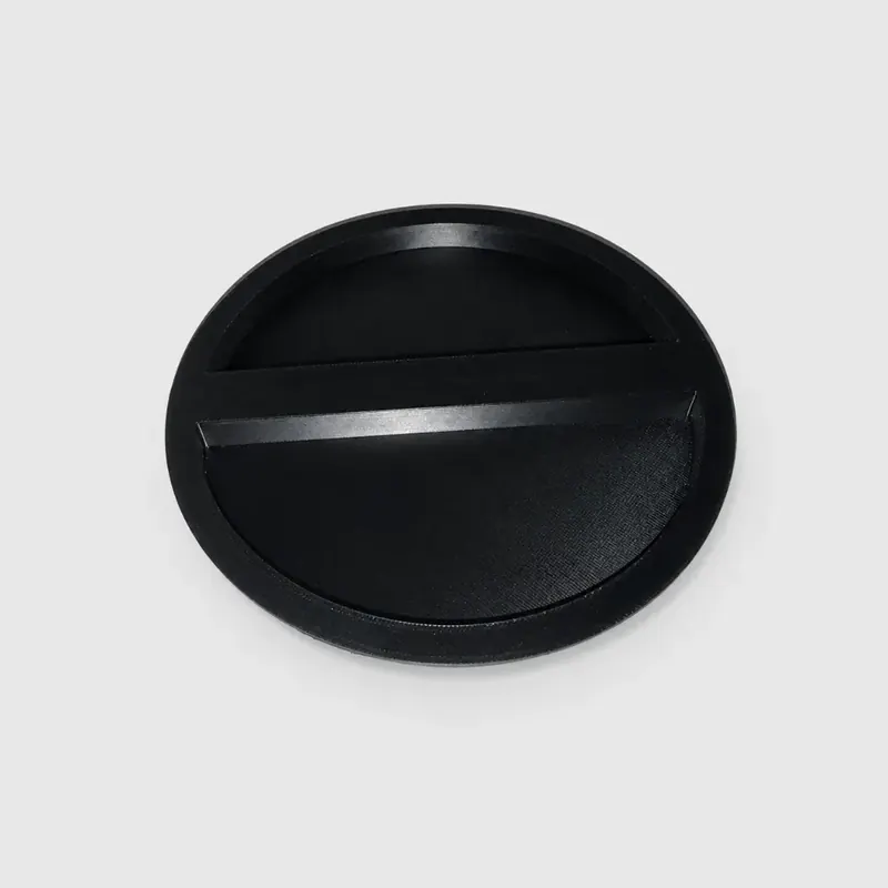 Bouchon rond noir imprimé en 3D, posé sur un fond blanc