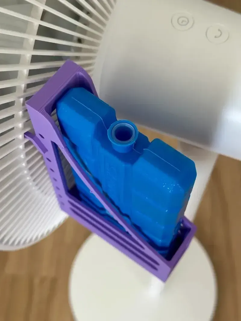 Support violet imprimé en 3D tenant un pain de glace bleu sur la grille d’un ventilateur
